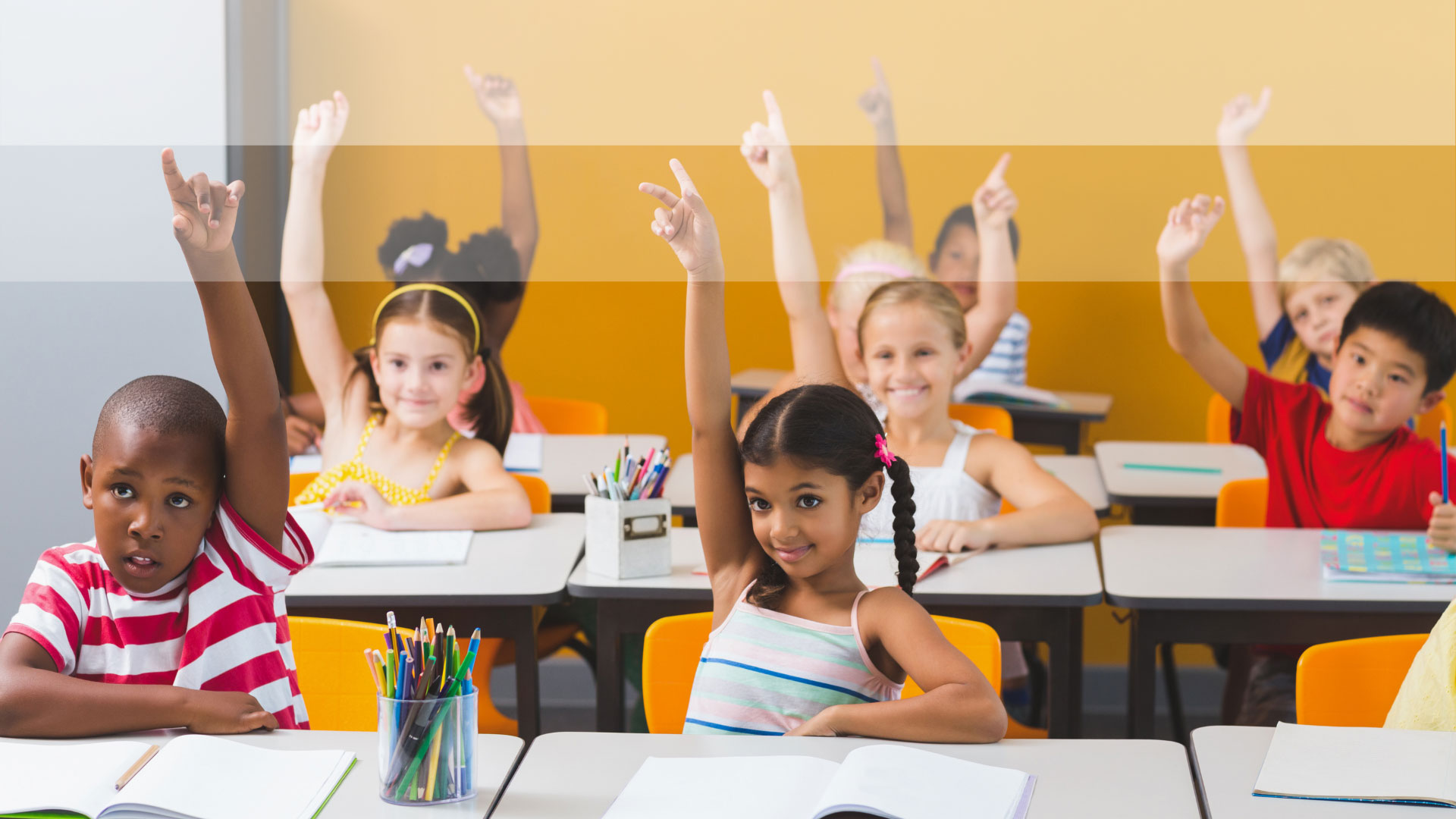 Children in a classroom with their hands raised
